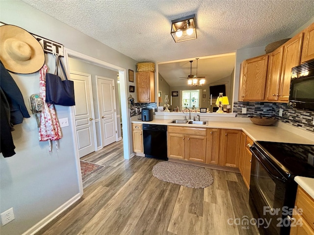 kitchen featuring black appliances, sink, light wood-type flooring, kitchen peninsula, and decorative backsplash