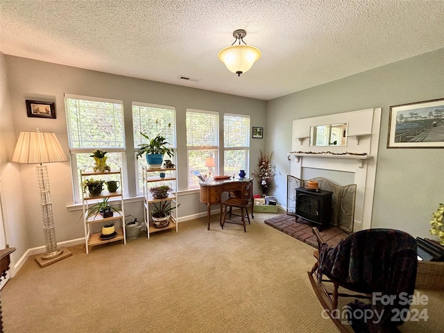 office with a wood stove, a textured ceiling, and carpet flooring