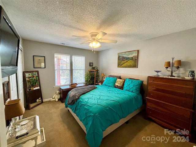 carpeted bedroom with ceiling fan and a textured ceiling