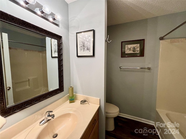 full bathroom featuring hardwood / wood-style flooring, toilet, shower / washtub combination, vanity, and a textured ceiling