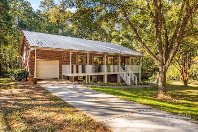 view of front of house with covered porch, a garage, and a front lawn