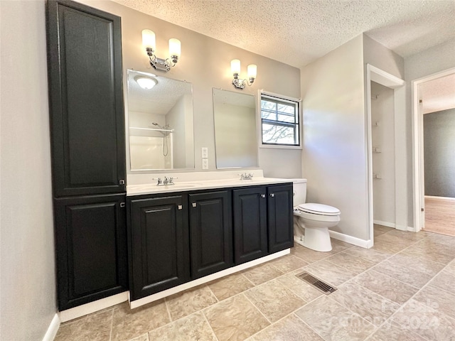 bathroom featuring vanity, walk in shower, toilet, and a textured ceiling