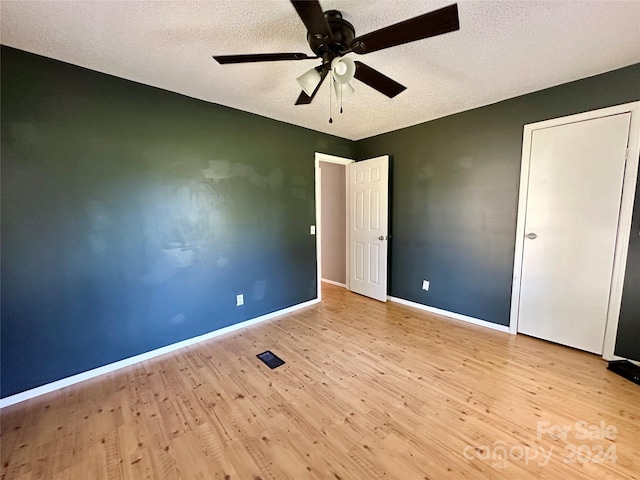 unfurnished bedroom with ceiling fan, a textured ceiling, and light hardwood / wood-style floors