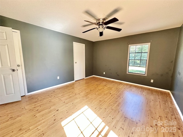 unfurnished room with a ceiling fan, baseboards, and wood finished floors