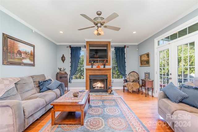 living room with a large fireplace, french doors, crown molding, and light wood-type flooring