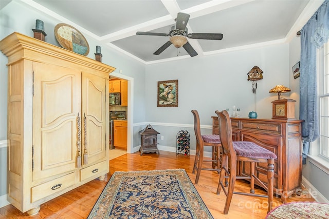 office space featuring ceiling fan, a wood stove, light hardwood / wood-style floors, coffered ceiling, and ornamental molding