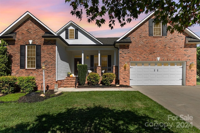 view of front of home featuring a garage, a porch, and a lawn