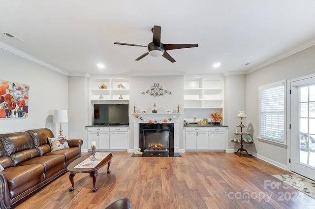 living room with ornamental molding, wood-type flooring, and ceiling fan