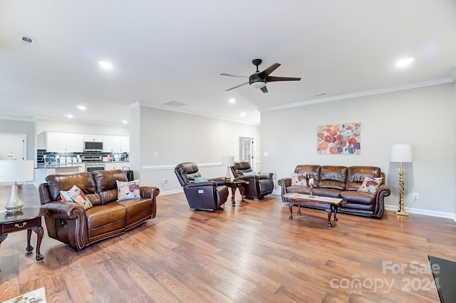 living room featuring ornamental molding, light hardwood / wood-style flooring, and ceiling fan