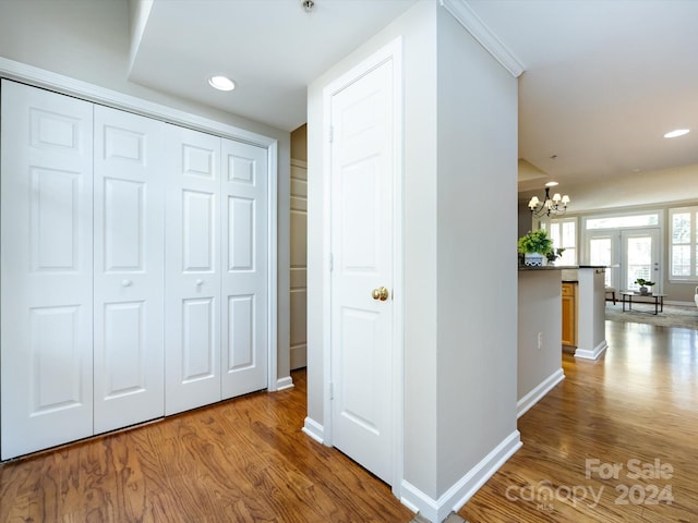 corridor featuring french doors, an inviting chandelier, and hardwood / wood-style floors