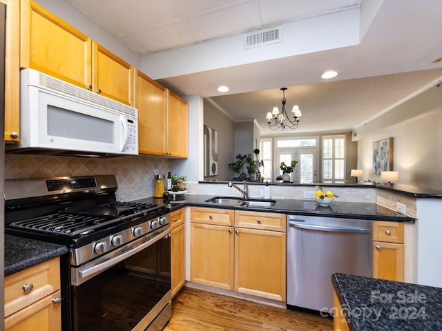 kitchen with stainless steel appliances, sink, a chandelier, light hardwood / wood-style floors, and tasteful backsplash