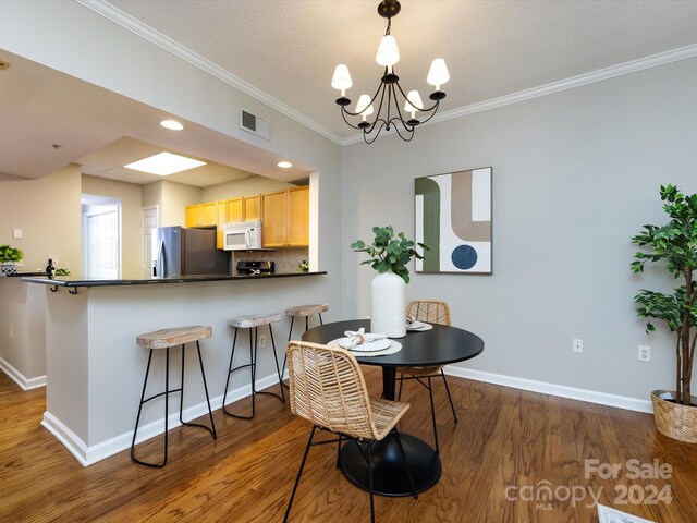 dining space featuring dark wood-type flooring, crown molding, and an inviting chandelier