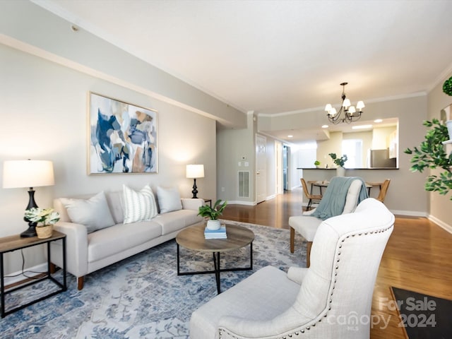 living room with hardwood / wood-style floors, a notable chandelier, and crown molding