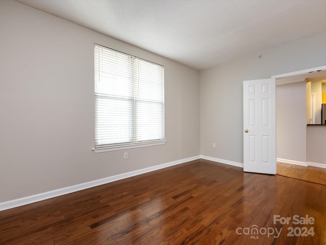 empty room featuring dark wood-type flooring and a textured ceiling