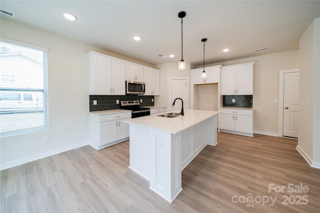 kitchen with white cabinetry, an island with sink, stainless steel appliances, and sink