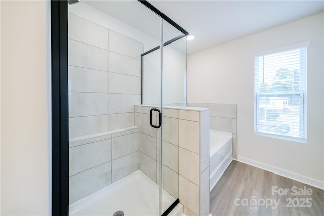 bathroom featuring plenty of natural light, independent shower and bath, and wood-type flooring