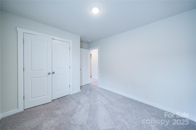 unfurnished bedroom with light colored carpet and a closet