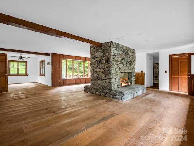 unfurnished living room featuring a fireplace, plenty of natural light, beamed ceiling, and hardwood / wood-style floors