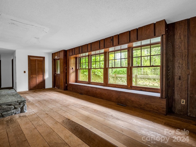 spare room with wooden walls, plenty of natural light, and light hardwood / wood-style flooring