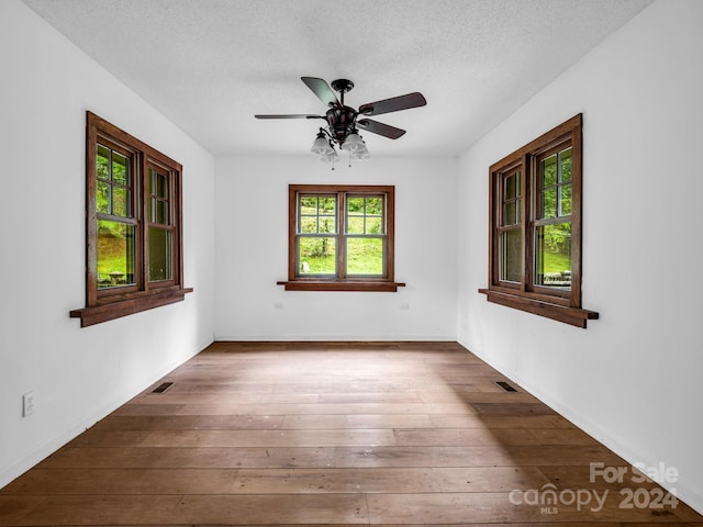 unfurnished room with ceiling fan, hardwood / wood-style flooring, and a textured ceiling