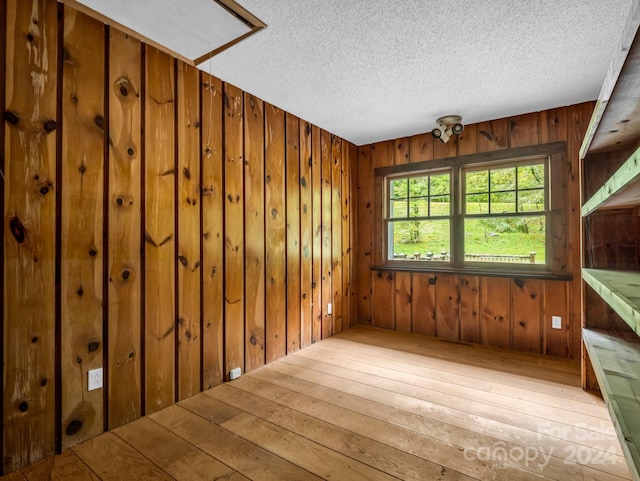 interior space with wood walls, light hardwood / wood-style floors, and a textured ceiling