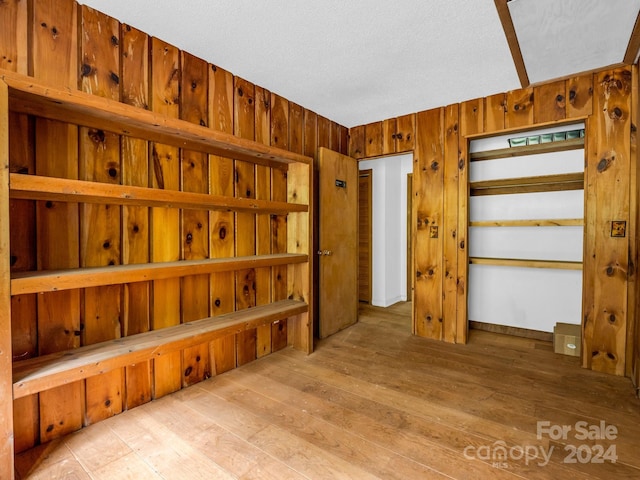 interior space with wooden walls, light hardwood / wood-style flooring, and a textured ceiling