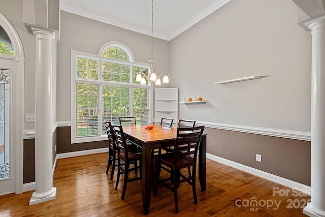 dining space with hardwood / wood-style flooring, an inviting chandelier, decorative columns, and crown molding