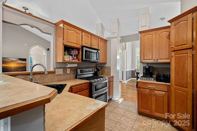 kitchen with tasteful backsplash, stainless steel appliances, vaulted ceiling, sink, and light tile patterned flooring