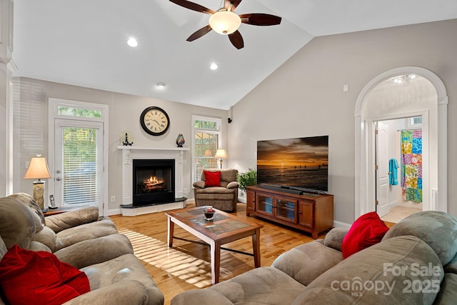 living room with high vaulted ceiling, ceiling fan, a wealth of natural light, and light hardwood / wood-style flooring