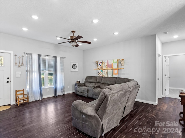 living room featuring ceiling fan, a textured ceiling, and dark wood-type flooring