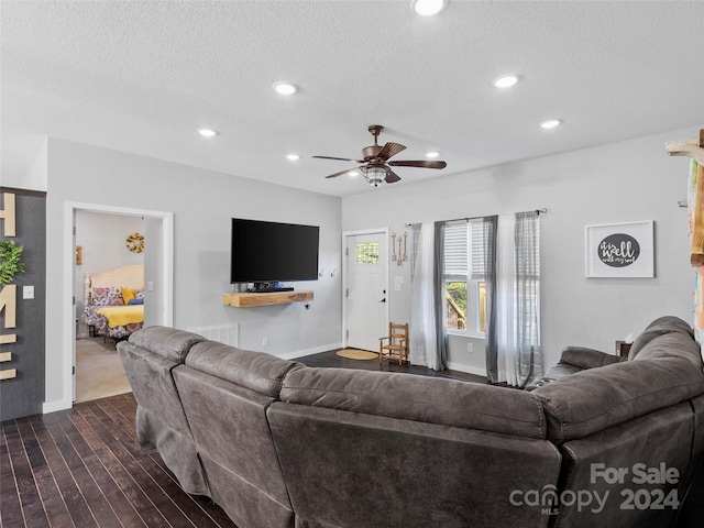 living room with ceiling fan, a textured ceiling, and dark hardwood / wood-style floors