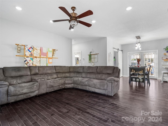 living room with ceiling fan, dark wood-type flooring, and a barn door