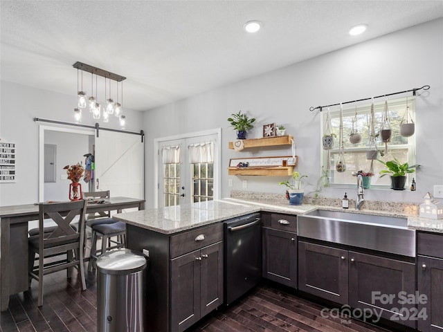 kitchen featuring light stone counters, kitchen peninsula, a healthy amount of sunlight, and a barn door