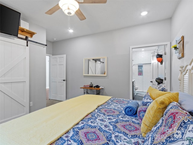 bedroom featuring a barn door, connected bathroom, and ceiling fan