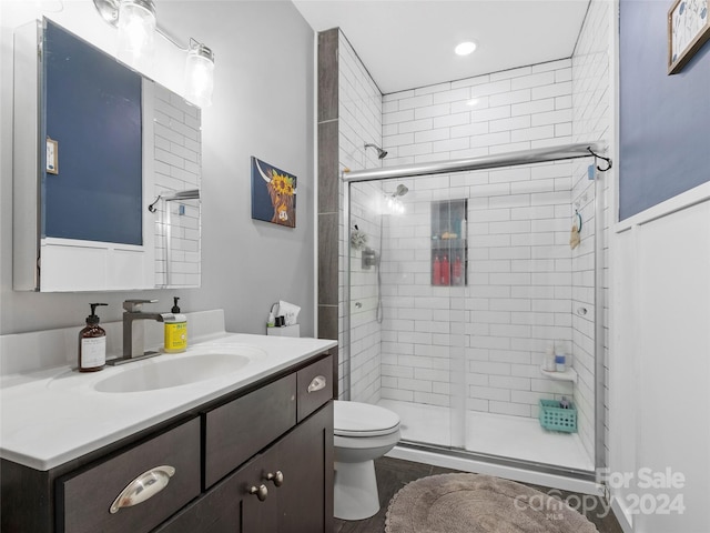 bathroom with hardwood / wood-style flooring, a shower with shower door, vanity, and toilet