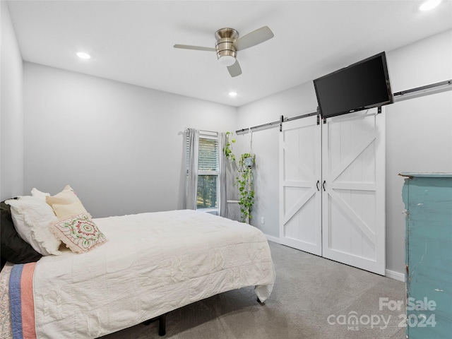 carpeted bedroom with ceiling fan and a barn door