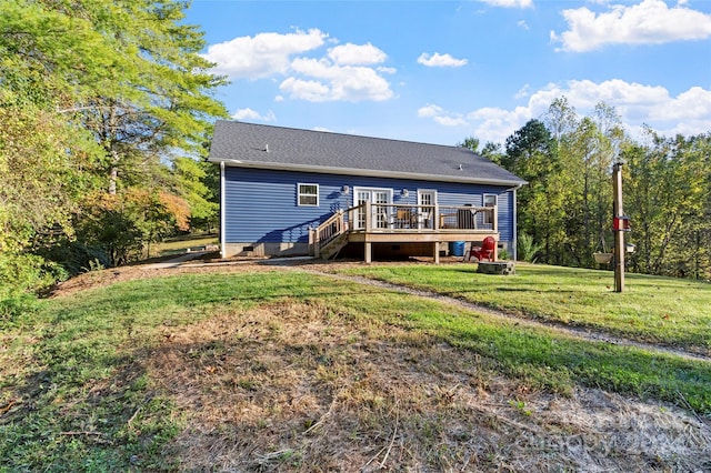 rear view of house featuring a wooden deck and a lawn