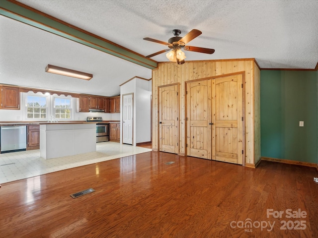 unfurnished living room with visible vents, light wood finished floors, lofted ceiling with beams, a textured ceiling, and crown molding