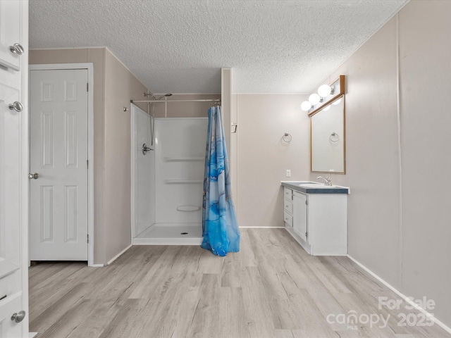 bathroom with vanity, a shower with shower curtain, wood finished floors, and a textured ceiling