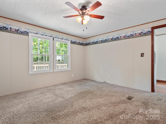 spare room featuring a ceiling fan, carpet, visible vents, and a textured ceiling