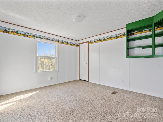 carpeted empty room featuring visible vents and a textured ceiling