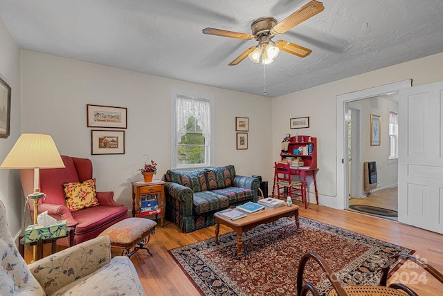 living room with wood-type flooring, heating unit, and ceiling fan