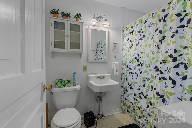 bathroom featuring sink, curtained shower, and toilet