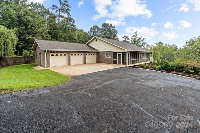 view of front of house featuring a front lawn, a sunroom, and a garage