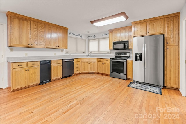 kitchen with appliances with stainless steel finishes, sink, and light hardwood / wood-style flooring