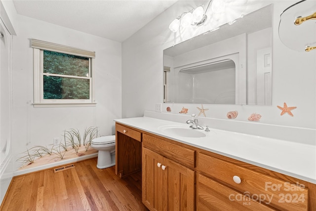 bathroom featuring vanity, toilet, a textured ceiling, a shower, and hardwood / wood-style floors