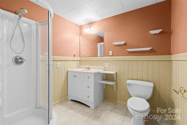 bathroom featuring vanity, wooden walls, a shower with shower door, and toilet