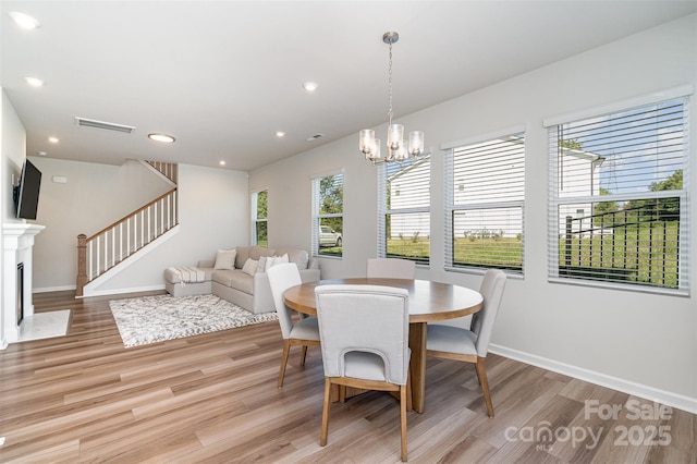 dining space with light hardwood / wood-style floors, a notable chandelier, and a wealth of natural light