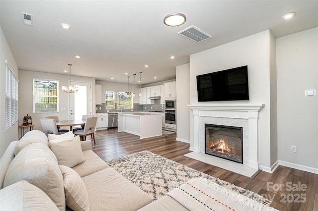 living room with a notable chandelier, a premium fireplace, and dark hardwood / wood-style flooring