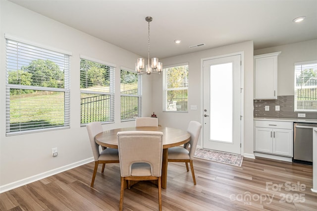 dining area with light hardwood / wood-style floors and a notable chandelier